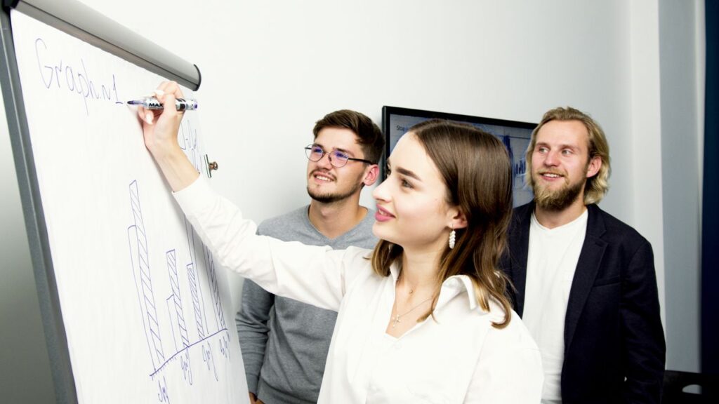 Mastering the First Impression: Your intriguing post title goes here Three professionals collaborating on a business graph presentation in an office setting.