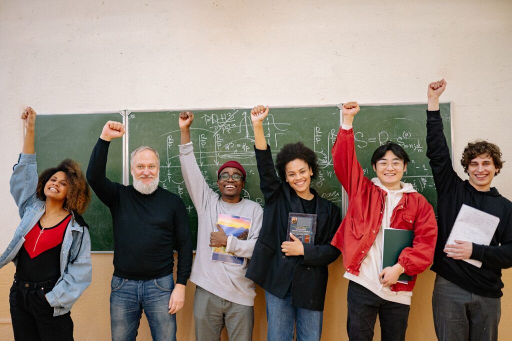 A cheerful group of diverse students and a teacher celebrating in front of a chalkboard full of equations.