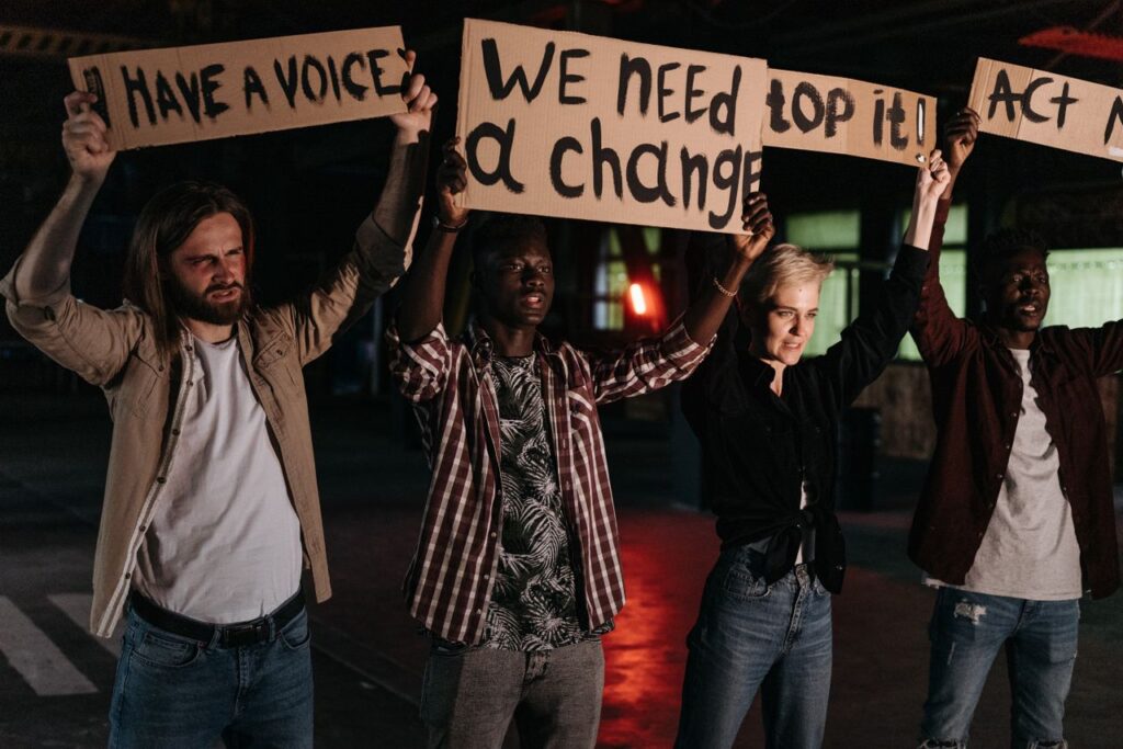 Crafting Captivating Headlines: Your awesome post title goes here Diverse group holding protest signs demanding change, highlighted by night lighting.
